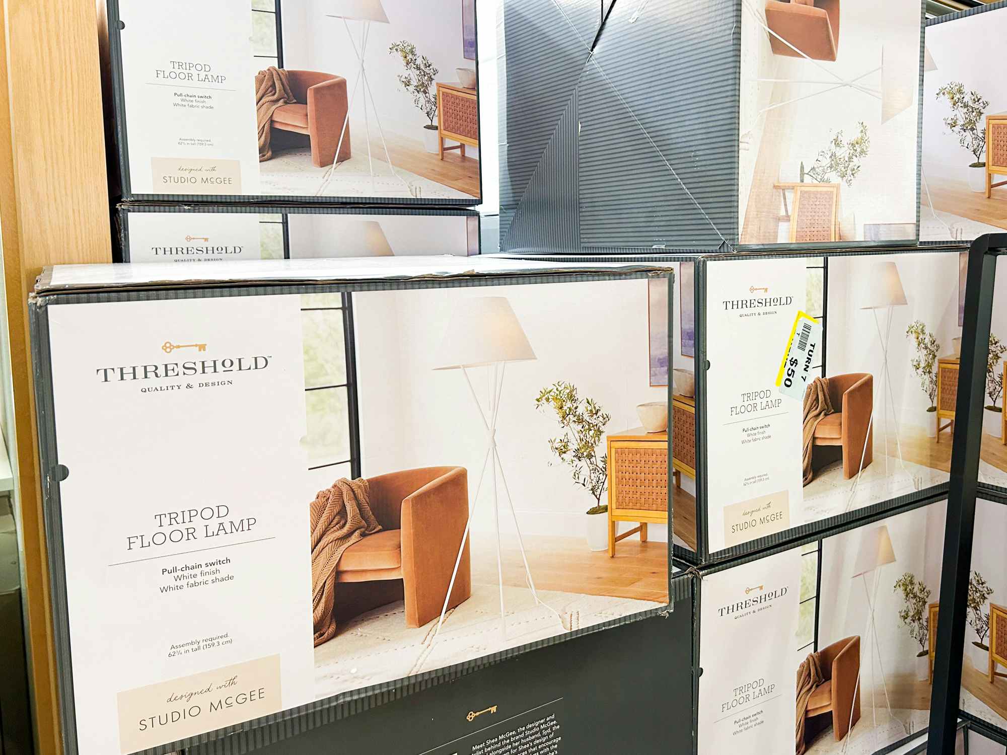 Tripod floor lamps in their boxes stacked at a Turn7 store
