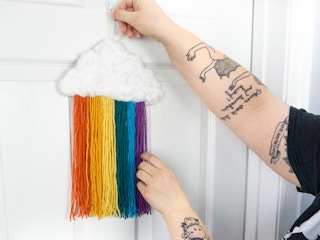 Someone hanging up a completed DIY rainbow cloud decoration