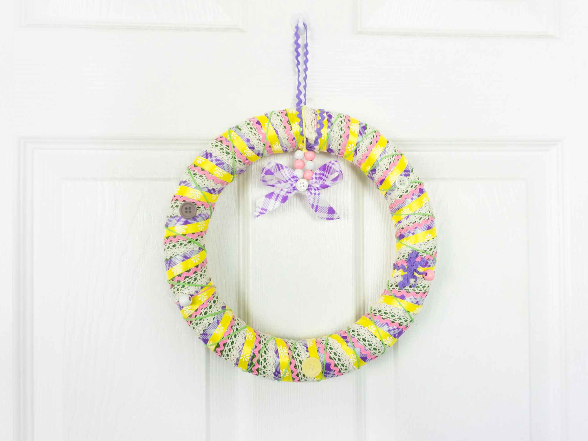 A completed ribbon wrapped wreath hanging on a white door
