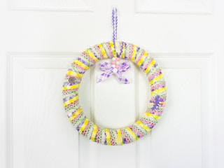A completed ribbon wrapped wreath hanging on a white door