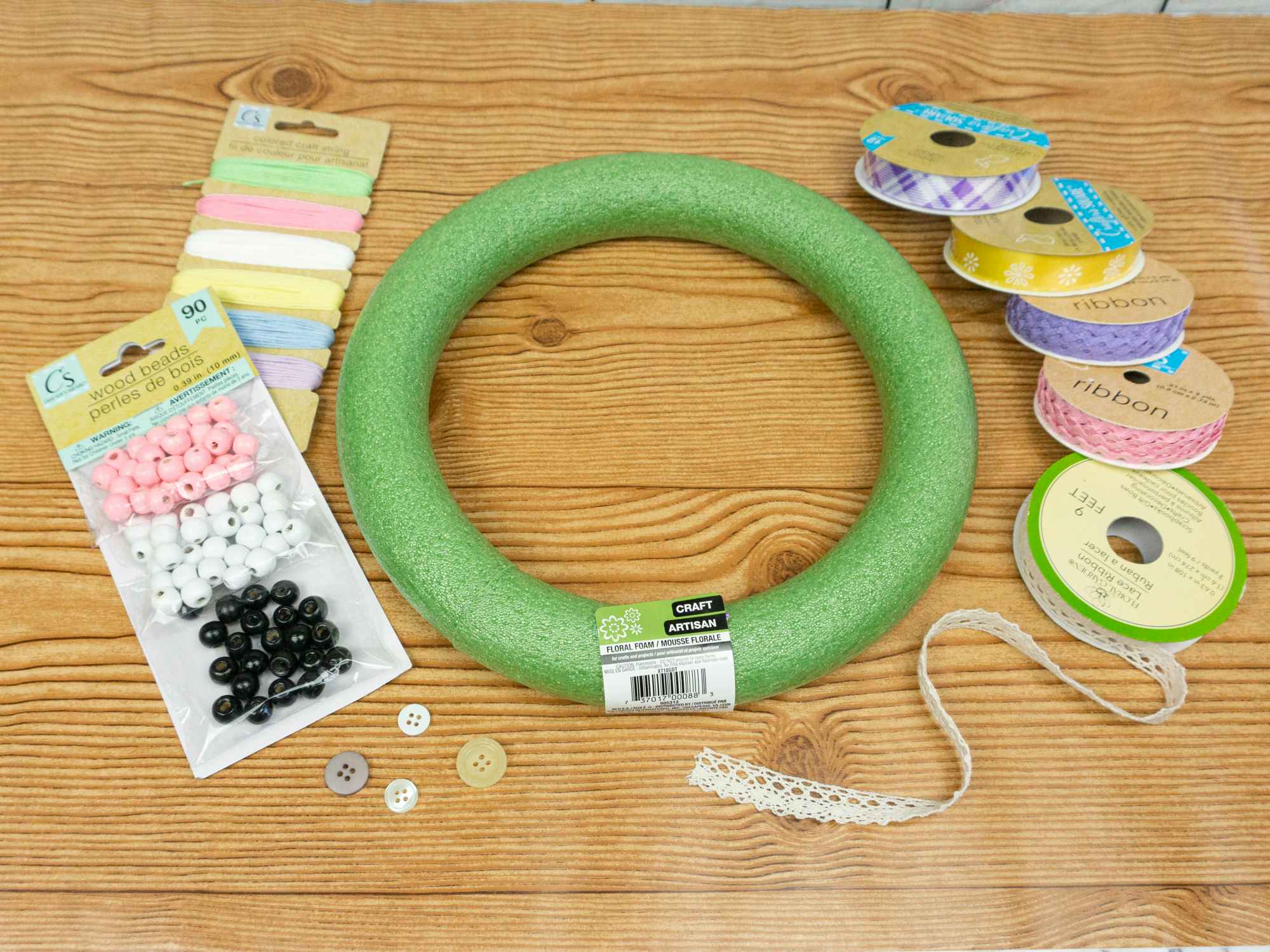 Materials for a spring wreath including several types of ribbon, wood beads, buttons, and a wreath form