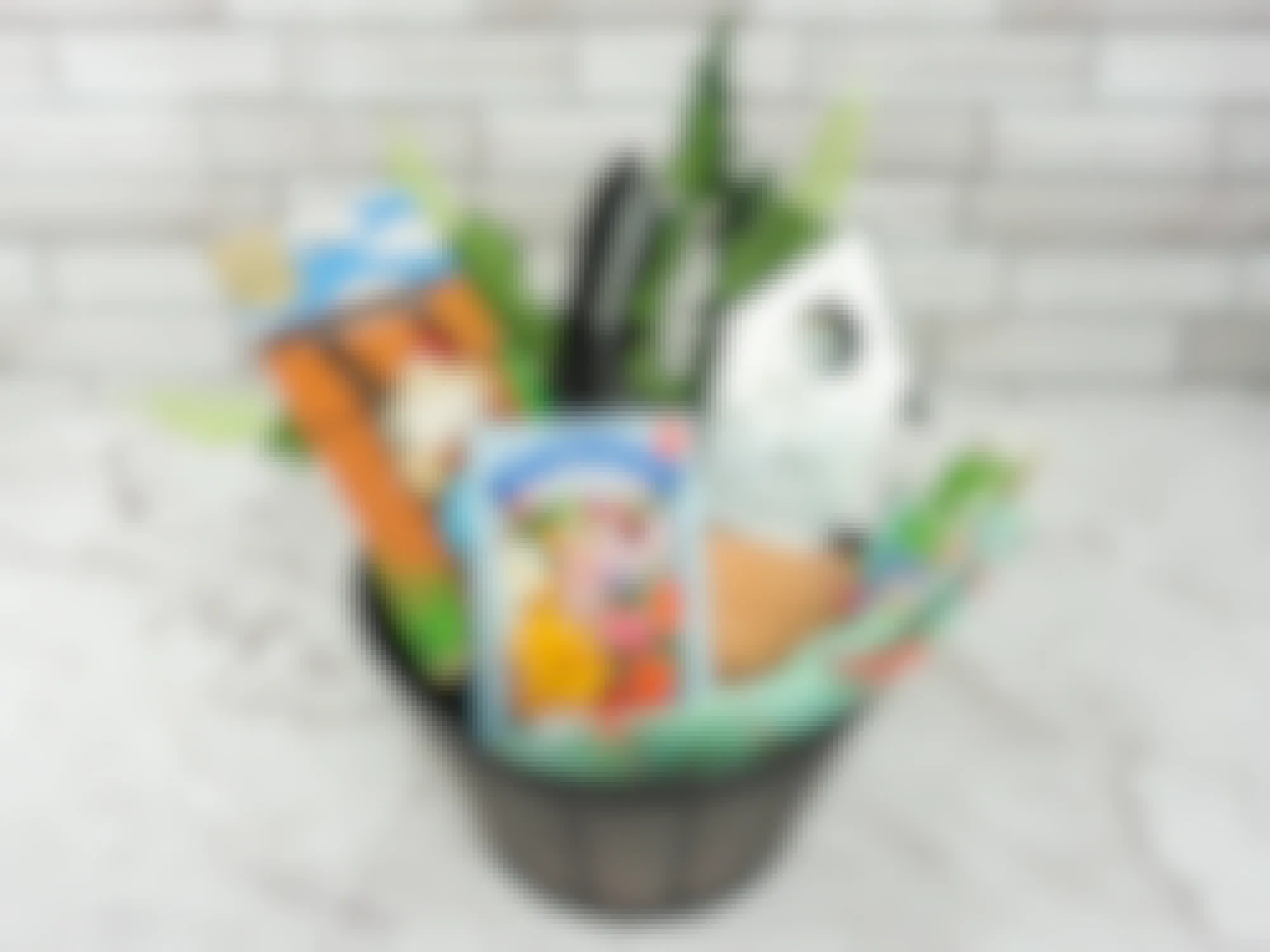 A gardening gift basket with a planter as the basket, and fake plants, gardening gloves, a trowel, some small pots, a little bird house, some seeds, and a gnome planter hugger inside