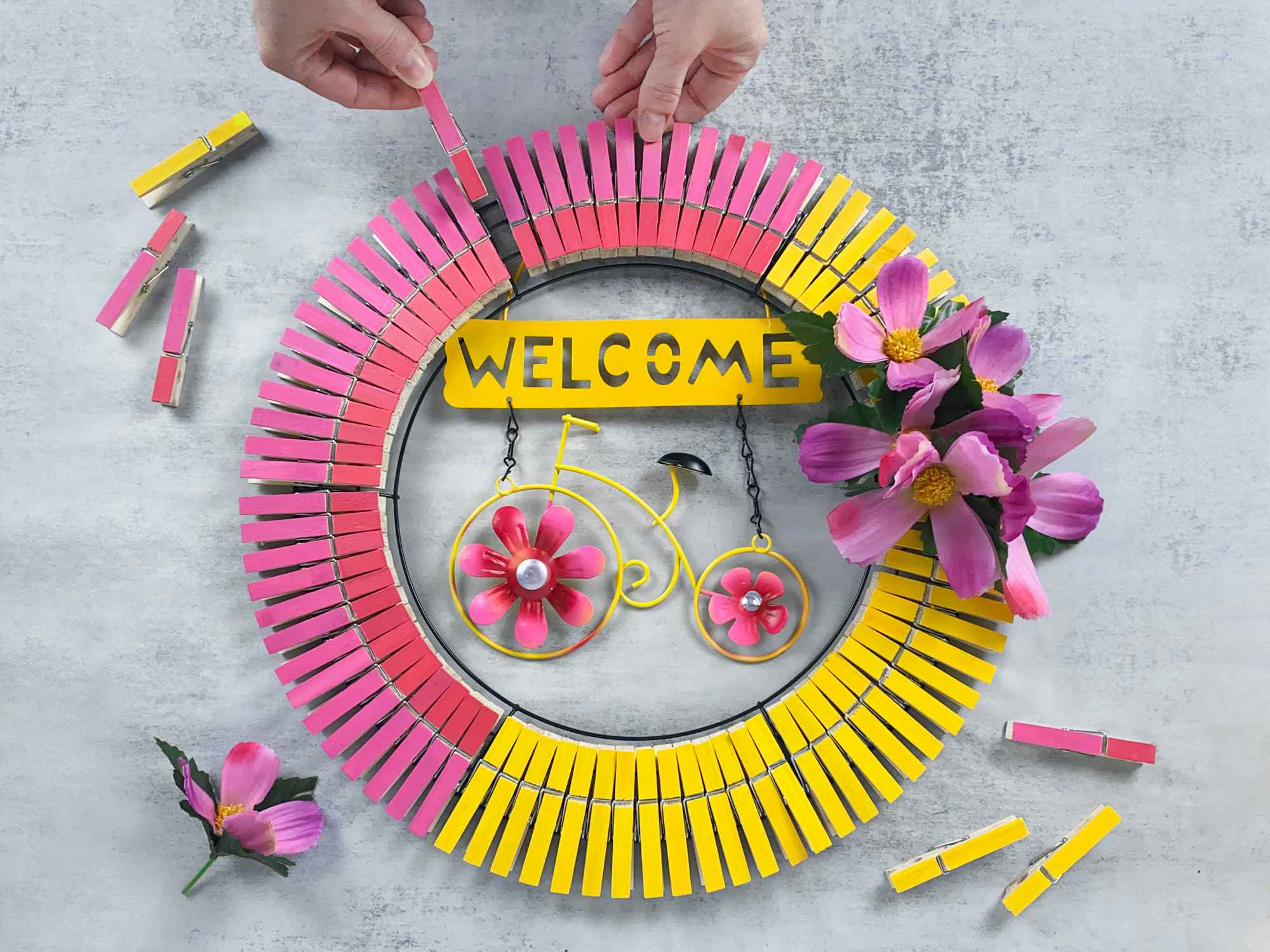 person making bright spring wreath with dollar tree garden sign and painted clothespins