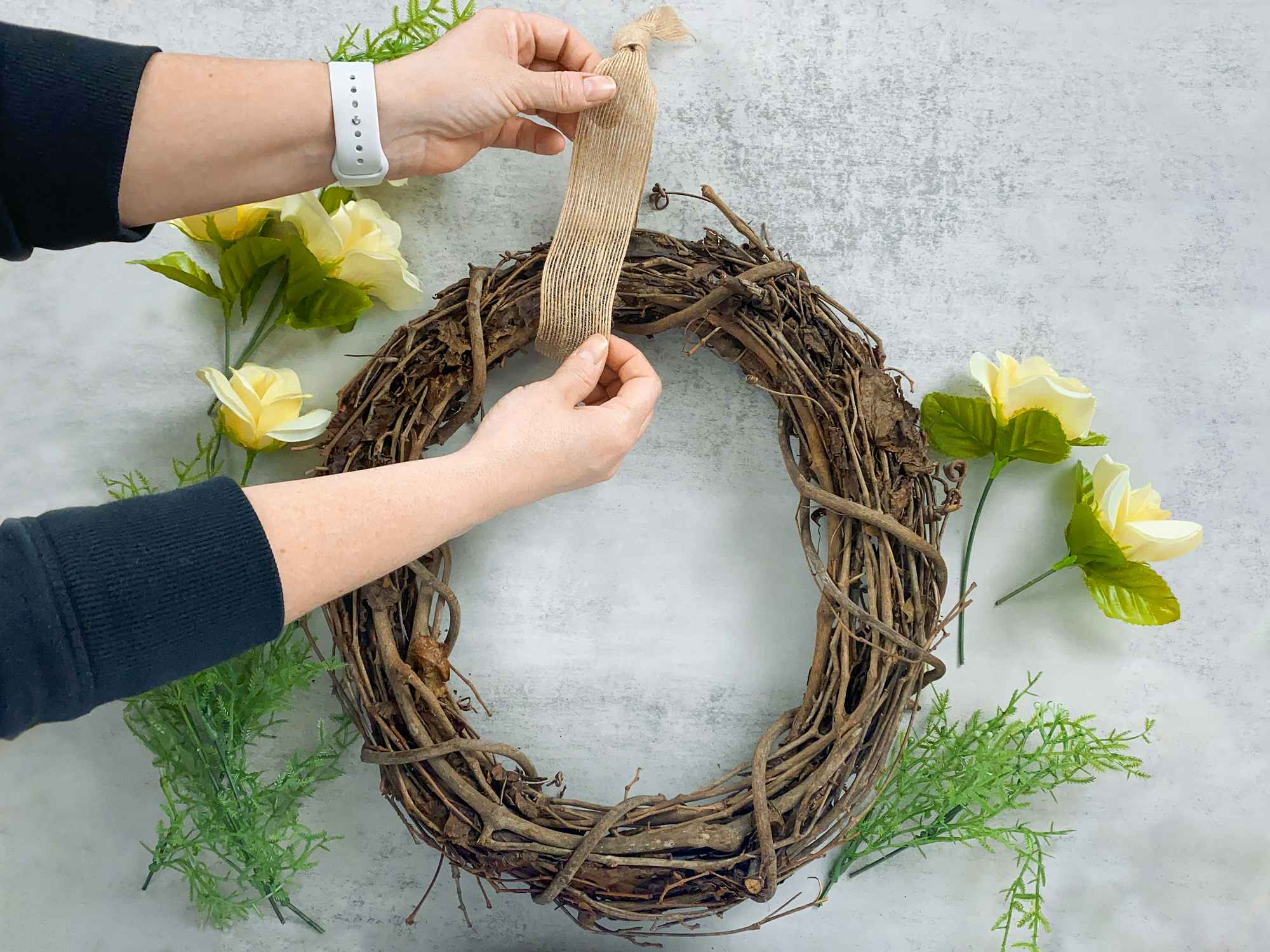 person making spring wreath with dollar tree artificial roses and foliage