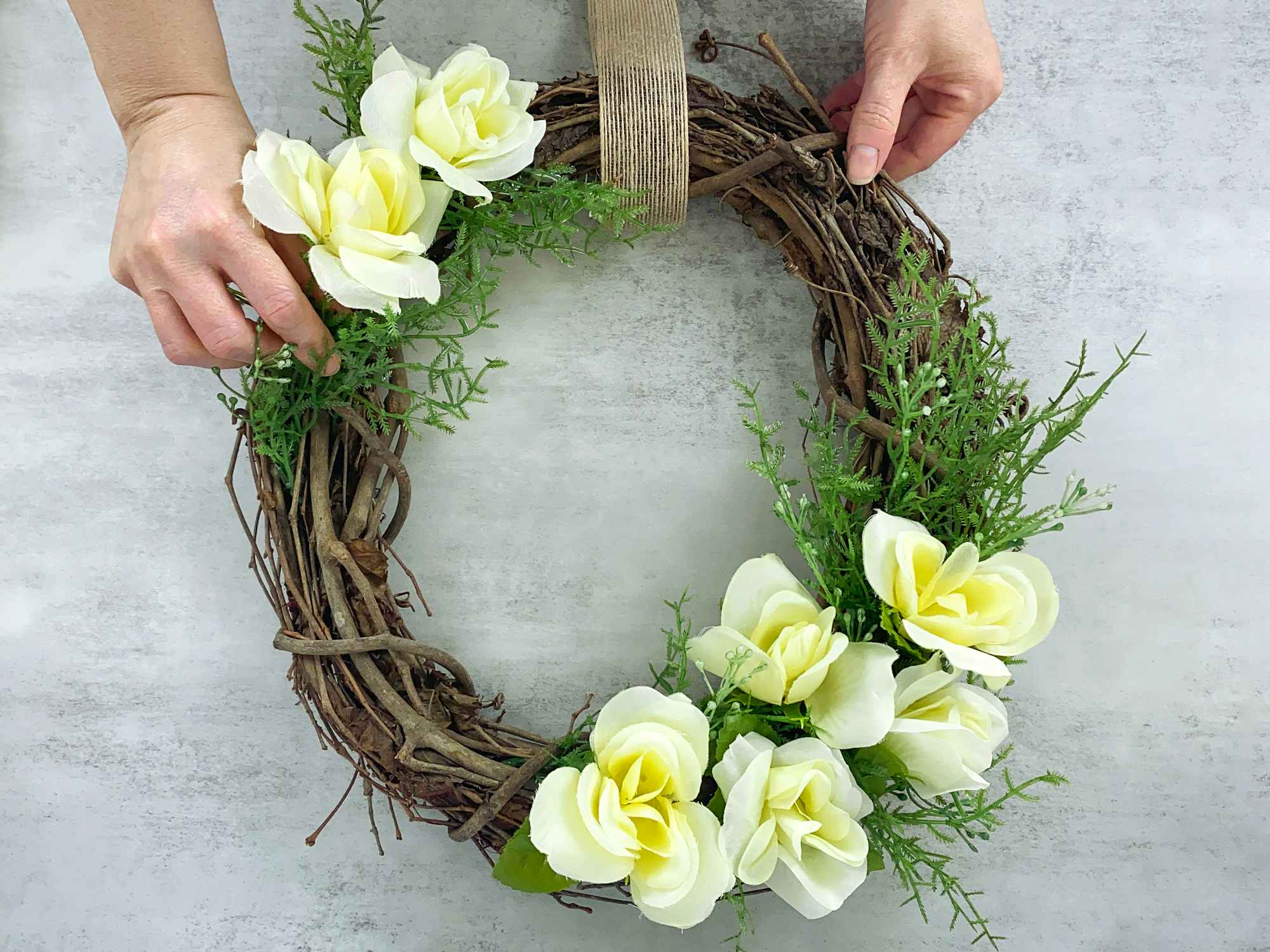 person making spring wreath with dollar tree artificial roses and foliage
