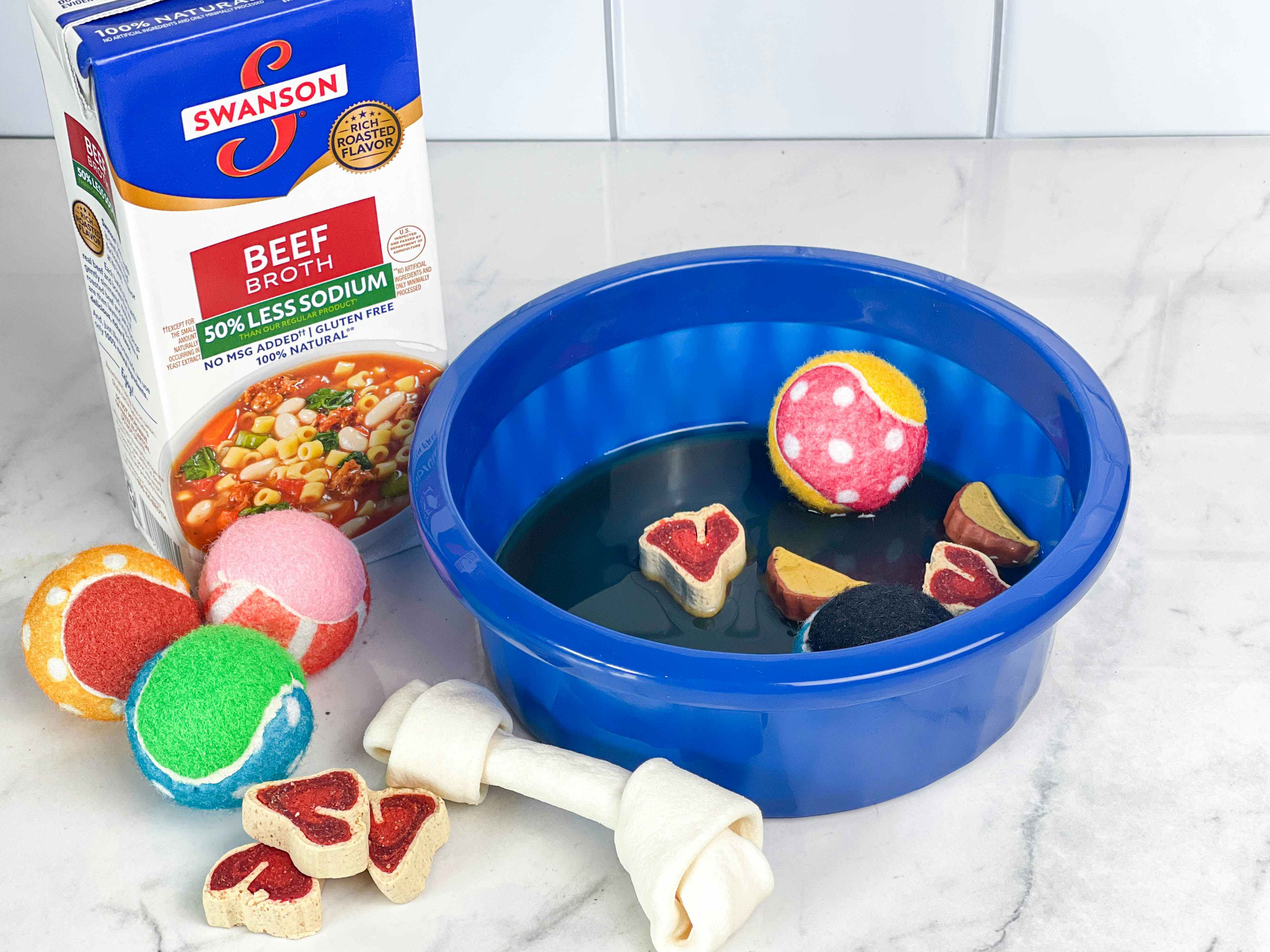 dog bowl with dog toys and treats with beef broth added sitting on counter
