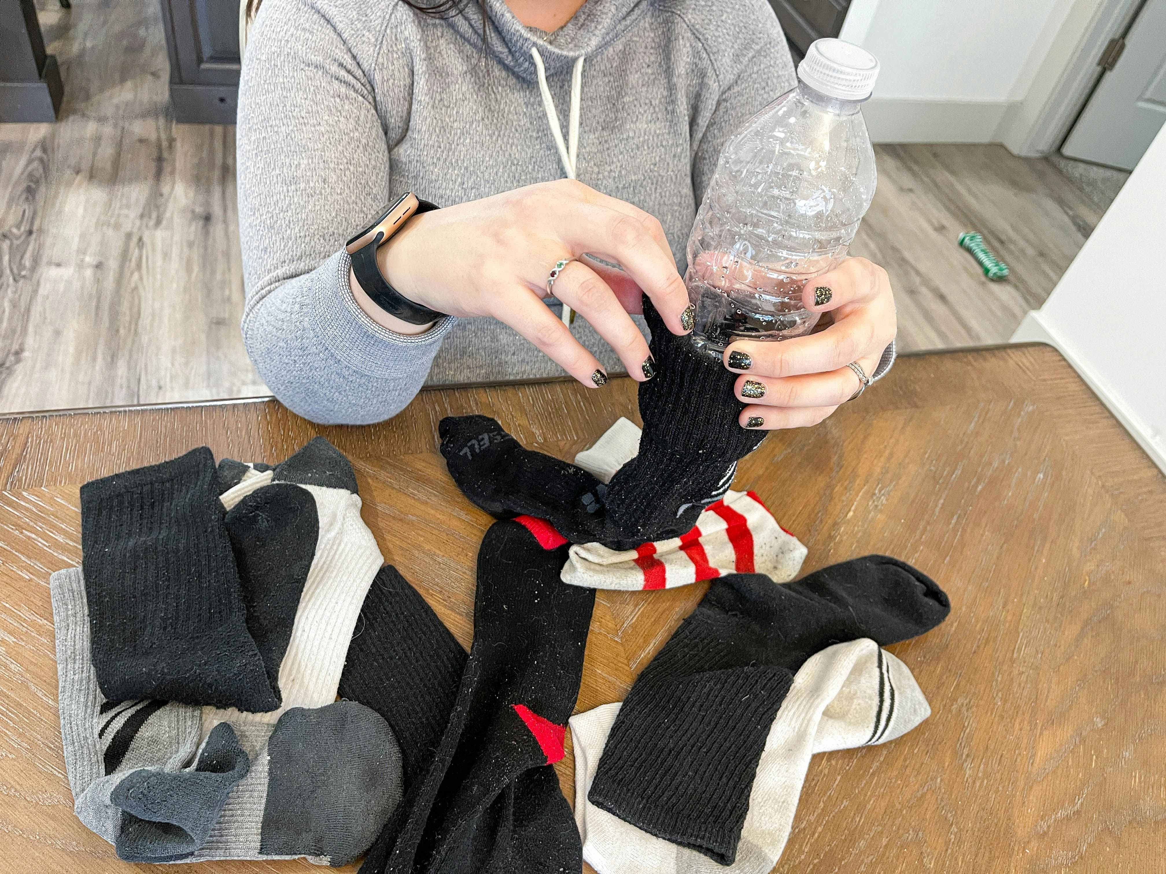 a person stuffing a sock with a empty plastic water bottle 