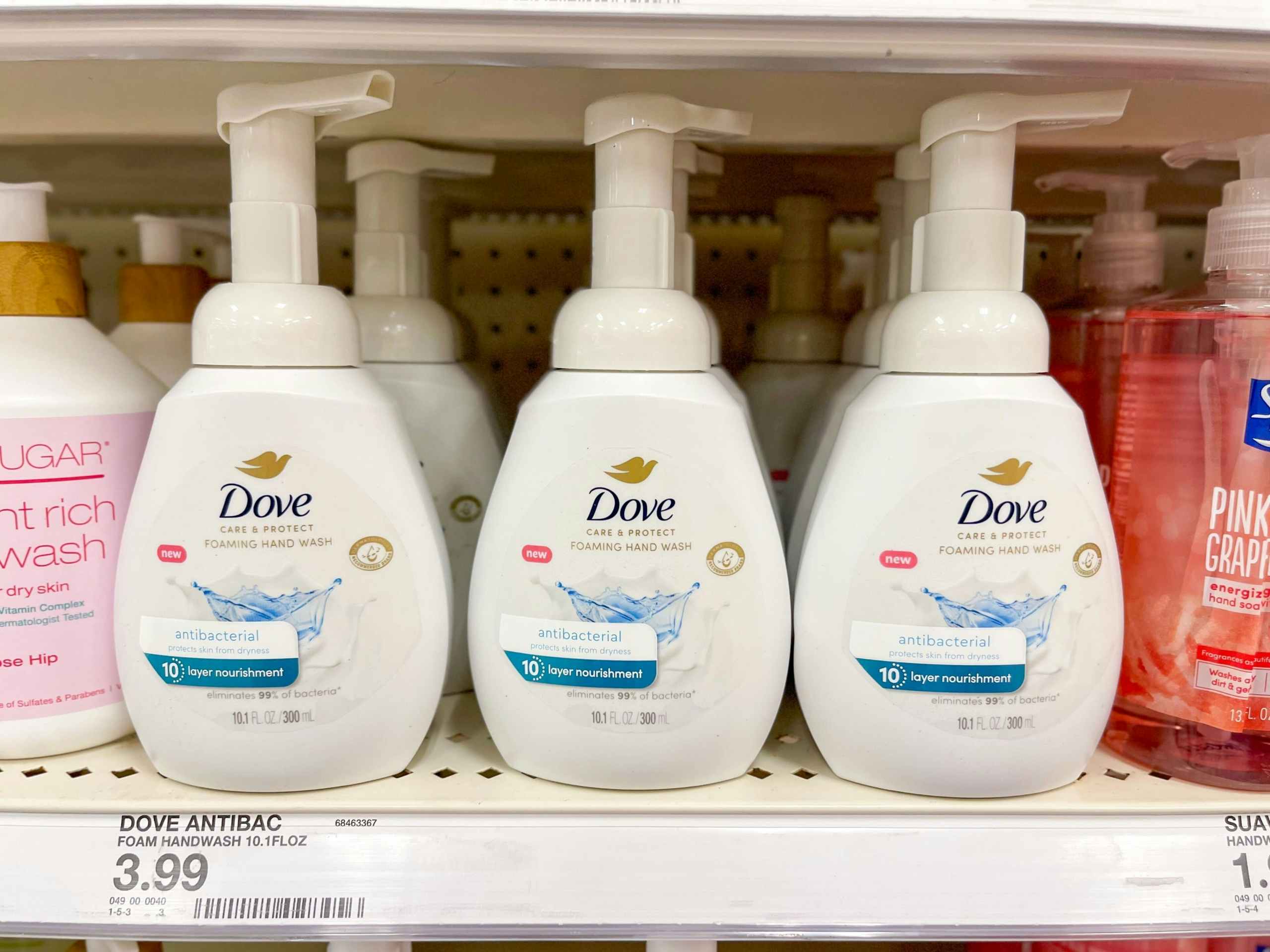 Several Dove hand soaps sitting on a store shelf.