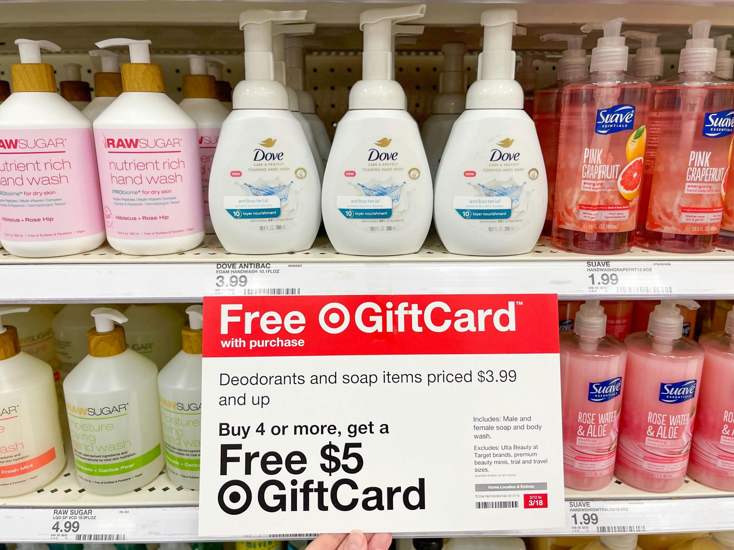 A store shelf with a variety of hand soaps sitting on a store shelf with a Free gift card poster attached to the shelf.