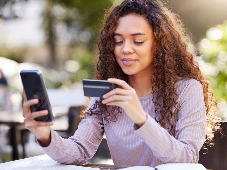 a person looking at their credit card while holding their phone