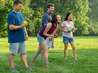 adults playing bocce ball game outside