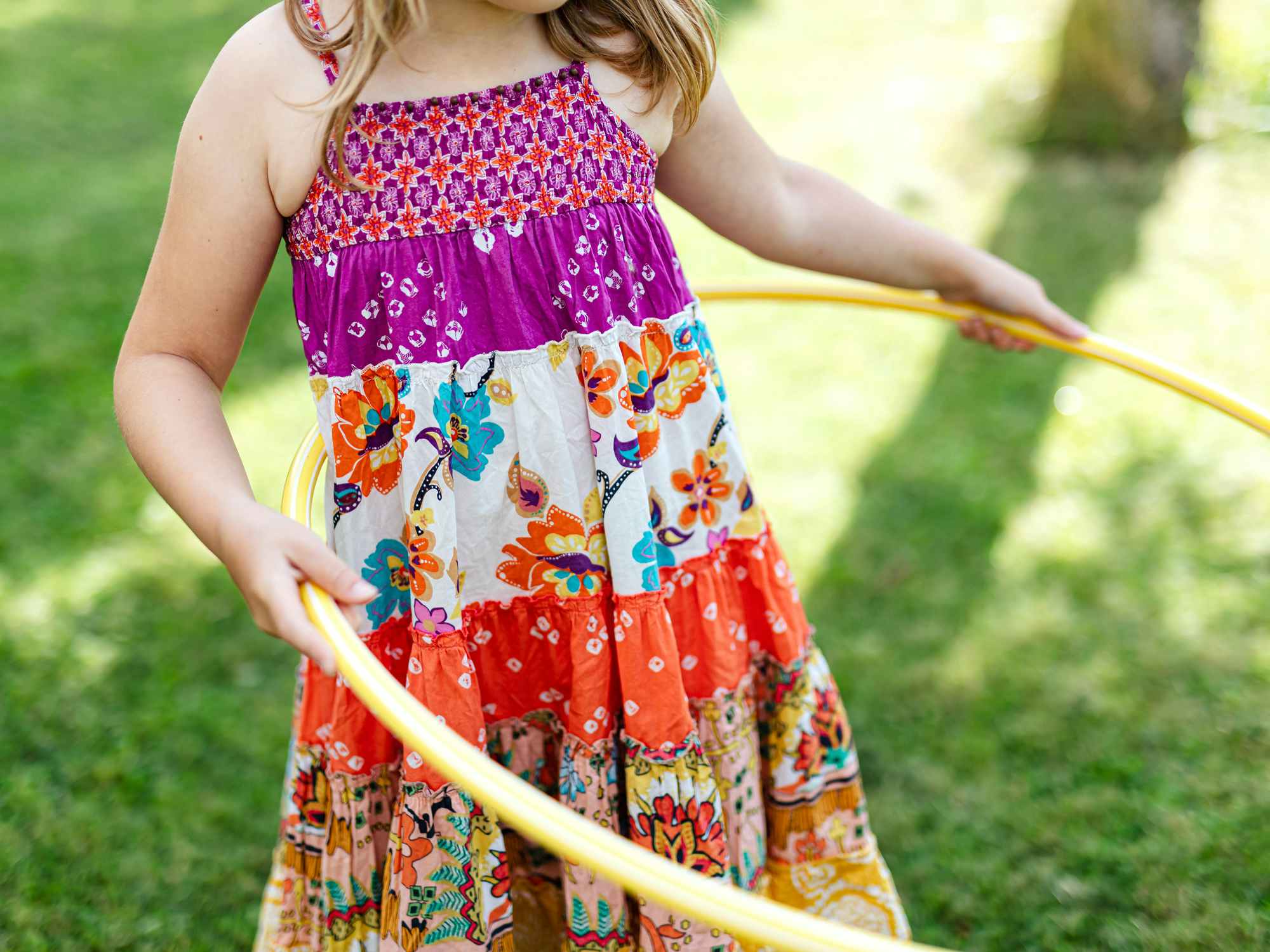 child in dress hula hooping outside