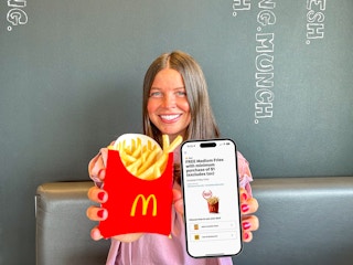 a person holding up fries and a phone with the mcdonalds app on it