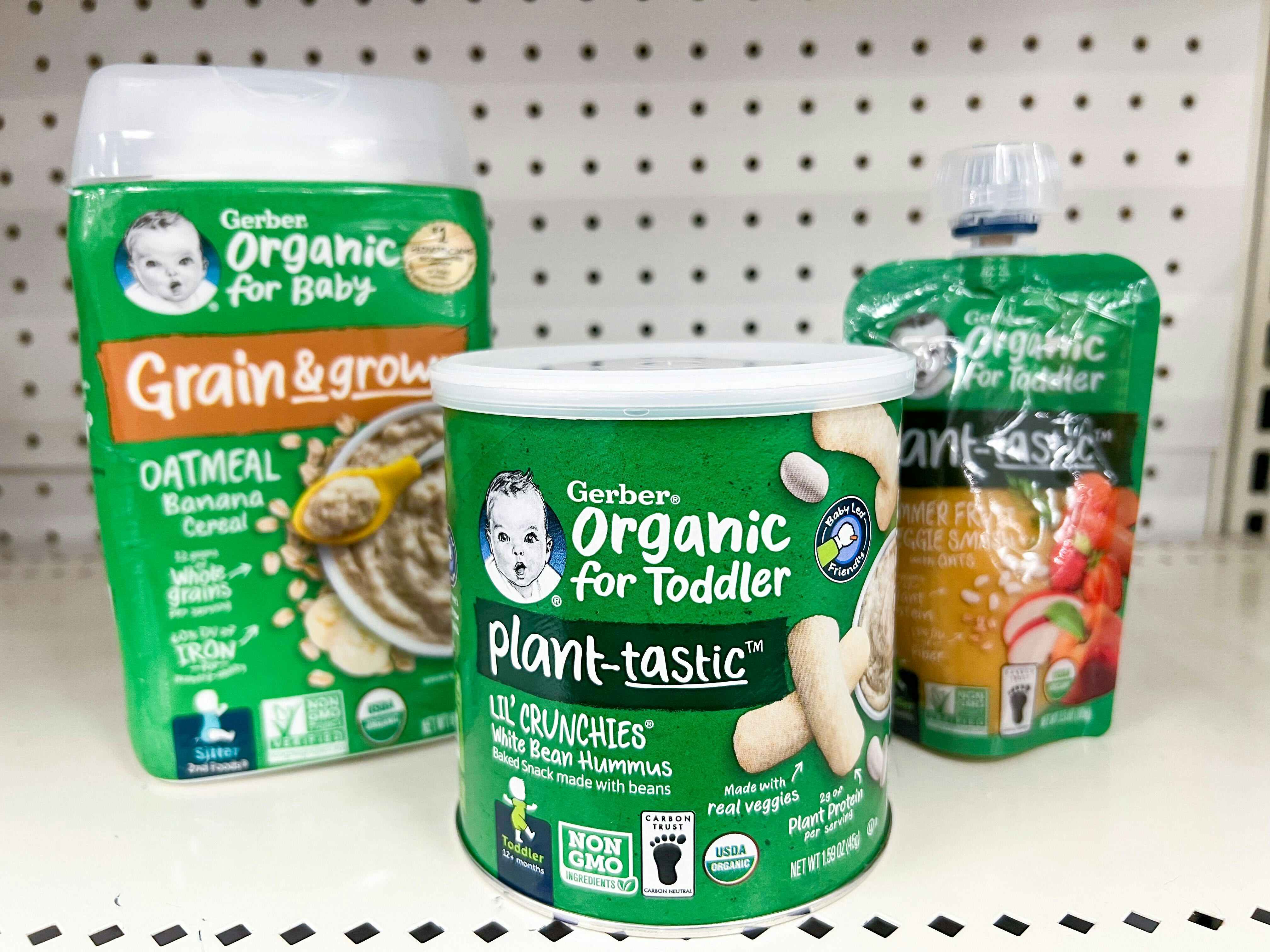 Three Gerber Organic baby products lined up on the shelf: Oatmeal banana cereal, plant-tastic lil' crunchies, and plant-tastic summer fruit and veggie smash with oats