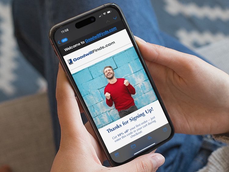Someone looking at their phone displaying an email from GoodwillFinds.com with a 10% off coupon