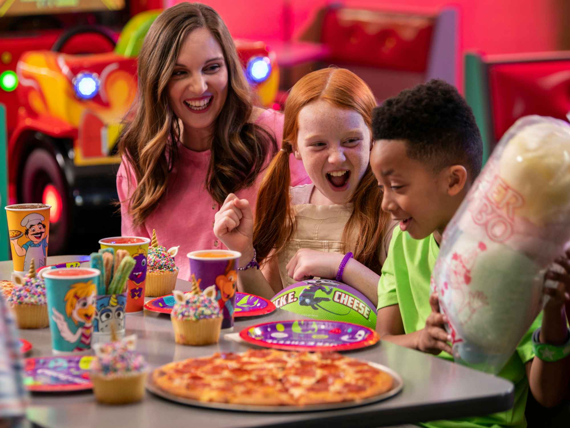 people sitting at a Chuck E. Cheese table laughing with food