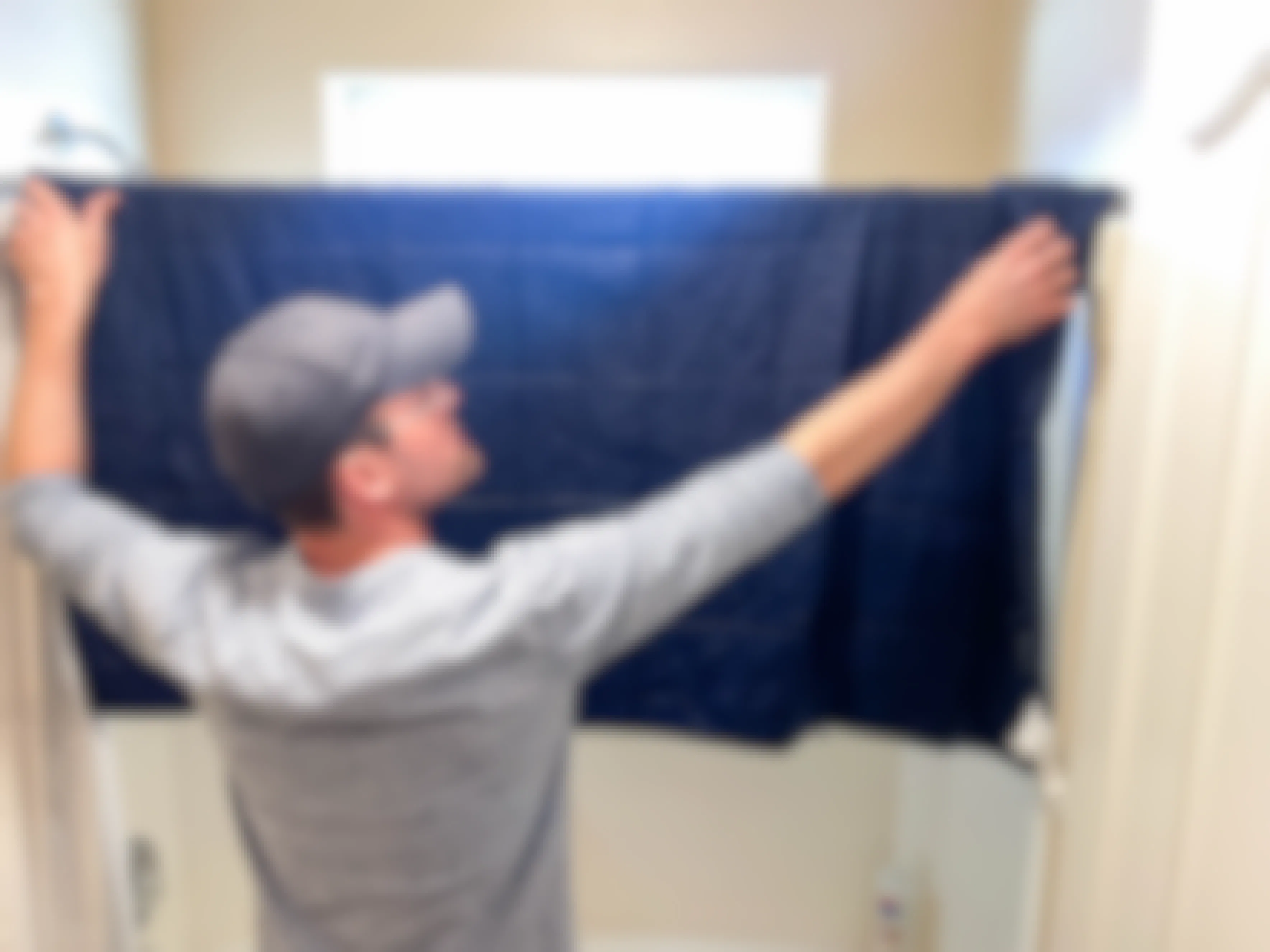 a man hanging a wet blanket on the shower curtain rod 
