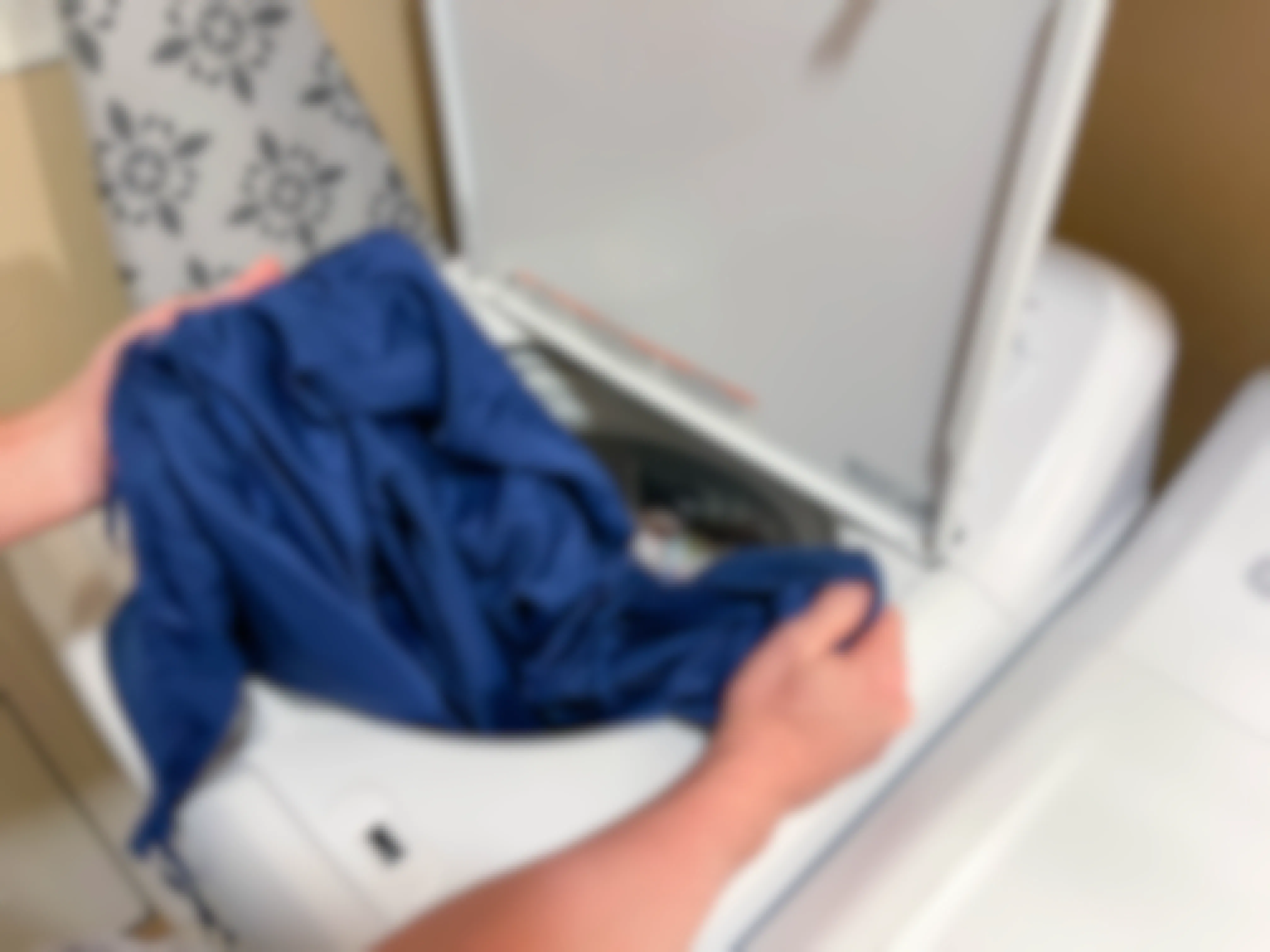 a person adding a blanket duvet cover into a washing machine 