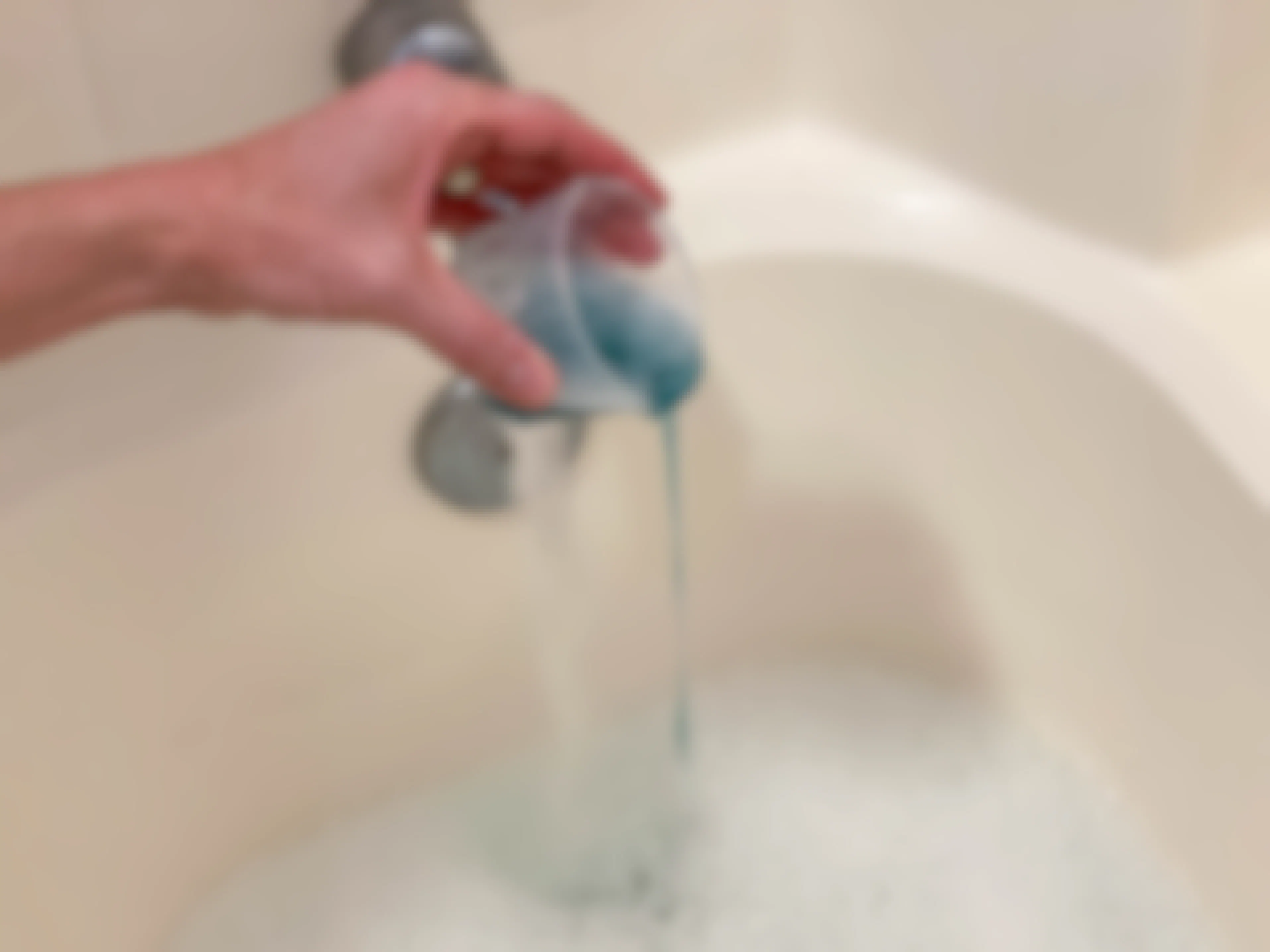 a person adding liquid detergent to a bathtub 