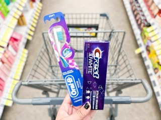 hand holding crest toothpaste and oral-b toothbrush