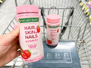 hand holding vitamins in shopping cart