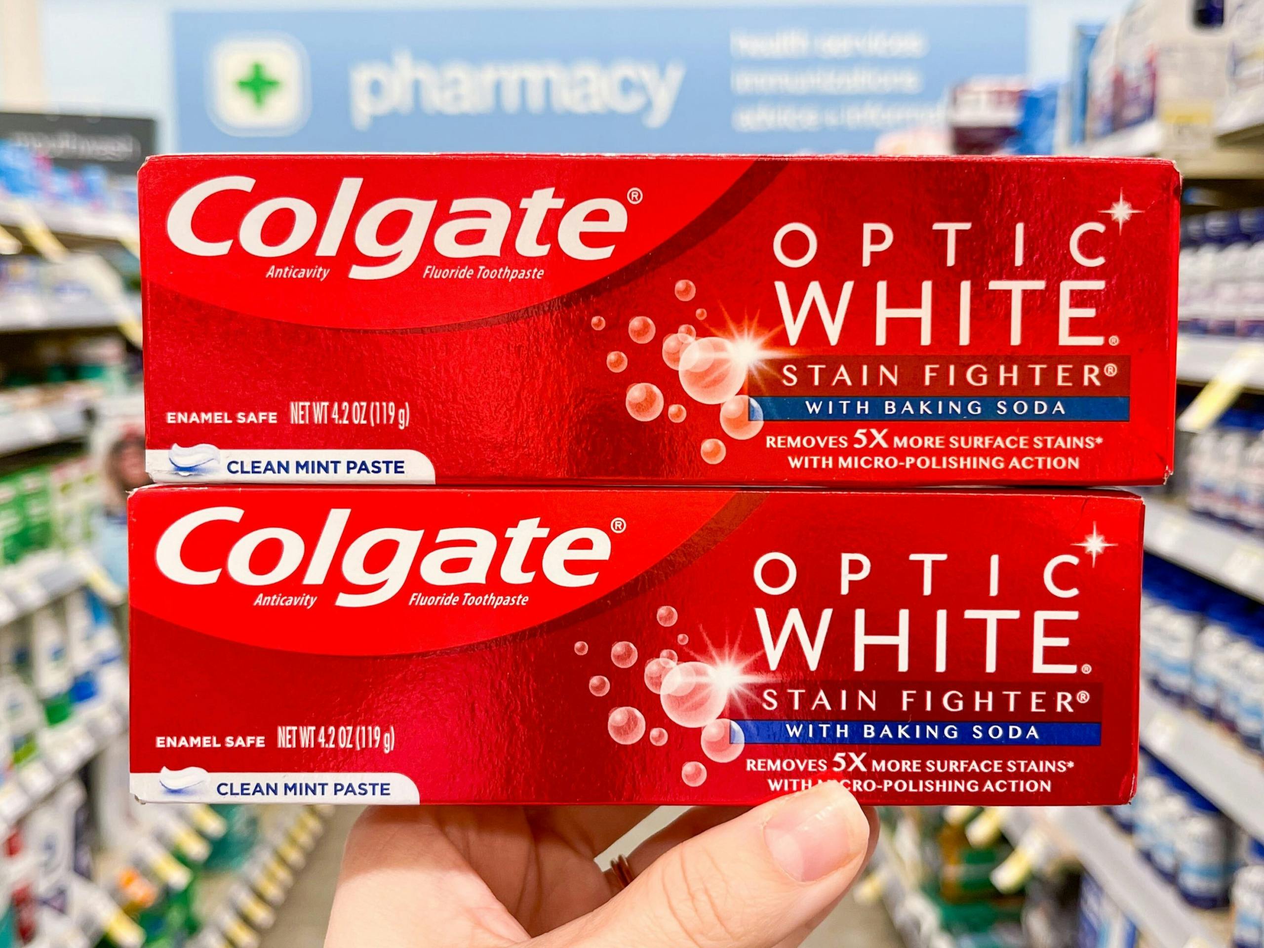 hand holding two boxes of colgate optic toothpaste