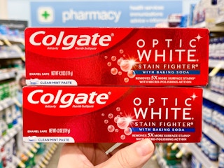 hand holding two boxes of colgate optic toothpaste