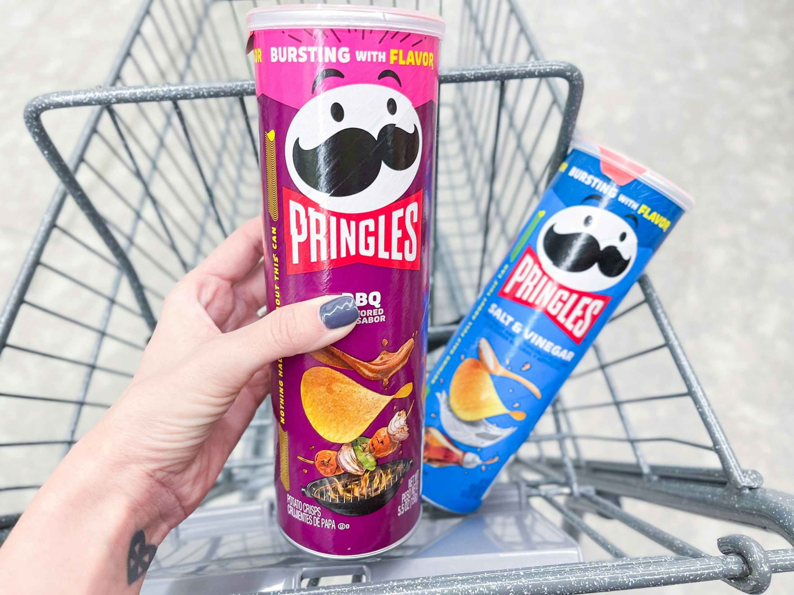 hand holding pringle can and pringle can in shopping cart