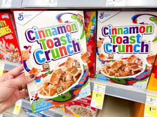 hand holding cinnamon toast crunch next to shelf