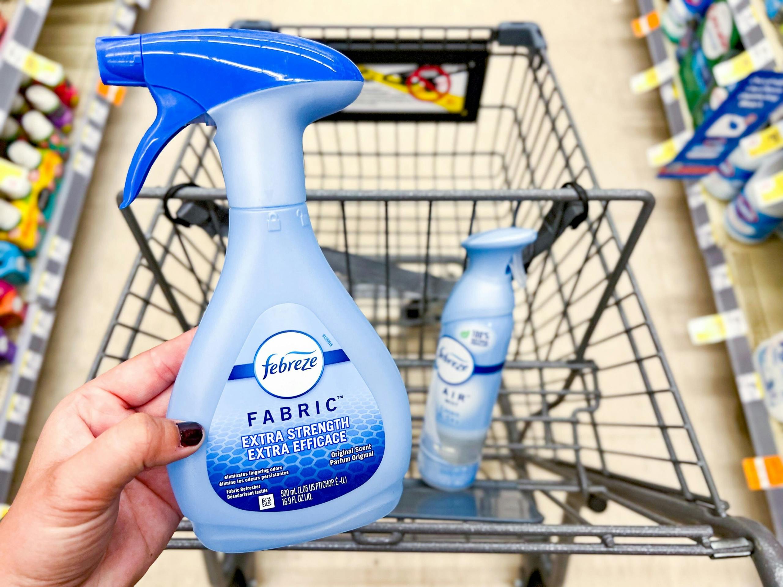 hand holding febreze fabric spray in front of shopping cart