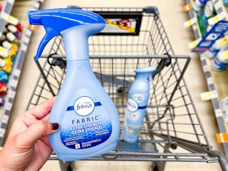 hand holding febreze fabric spray in front of shopping cart