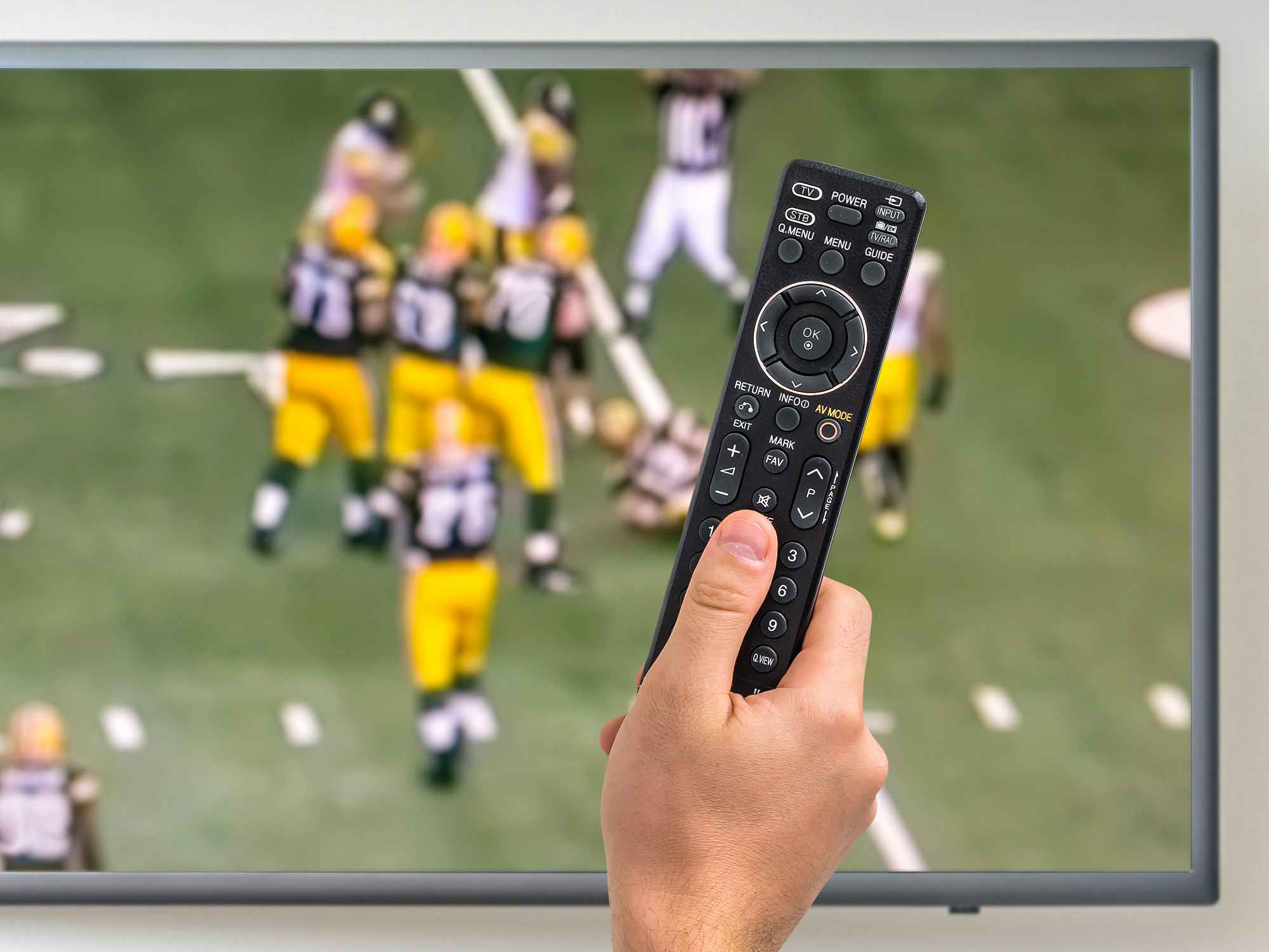 person watching nfl sunday ticket and holding remote