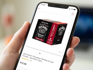 person holding phone with jack daniels coca-cola cans product screenshot