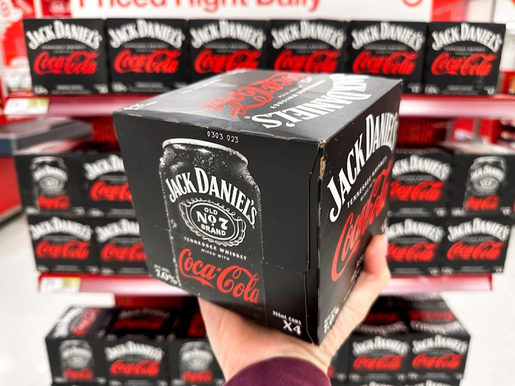 Someone holding a box of Jack Daniels Coca Cola cans in front of a shelf at Target