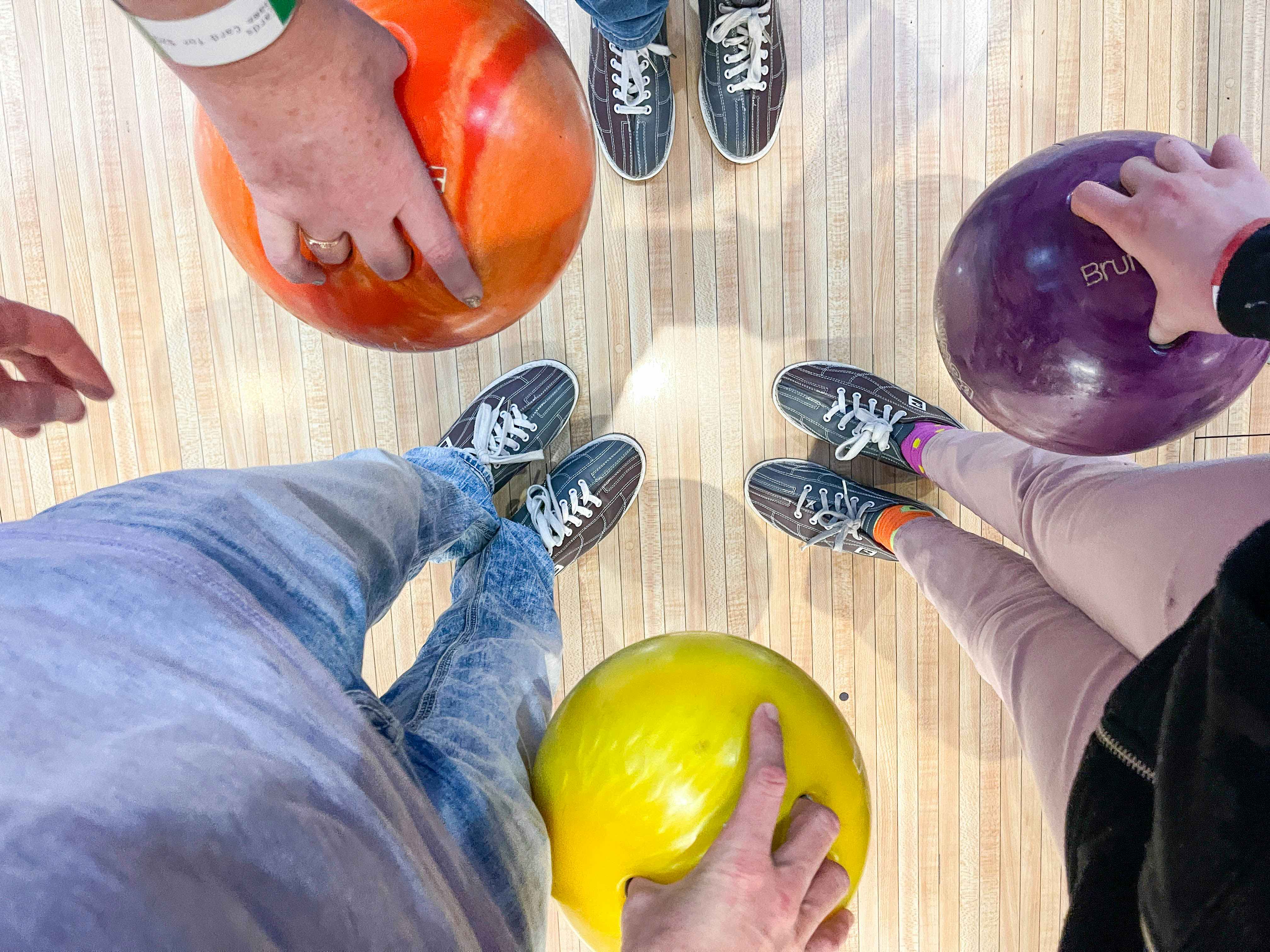 a family holding bowling balls and looking down at their shoes