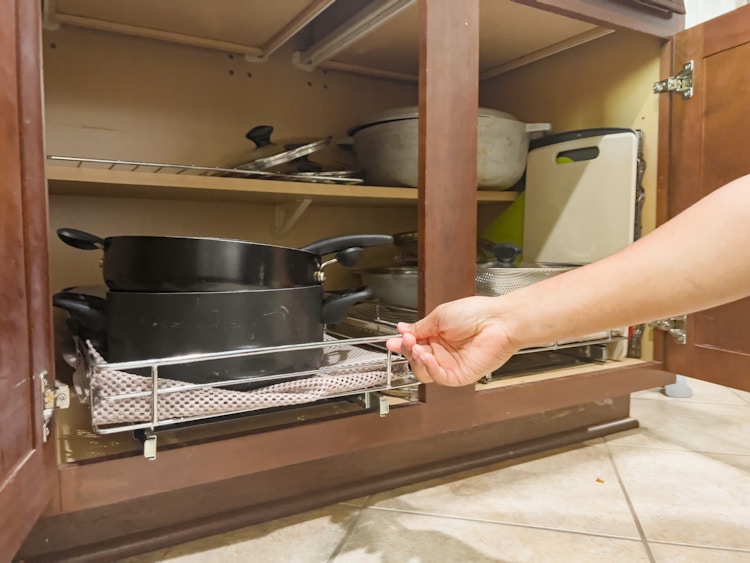 hand pulling on a sliding rack holding pots and pans