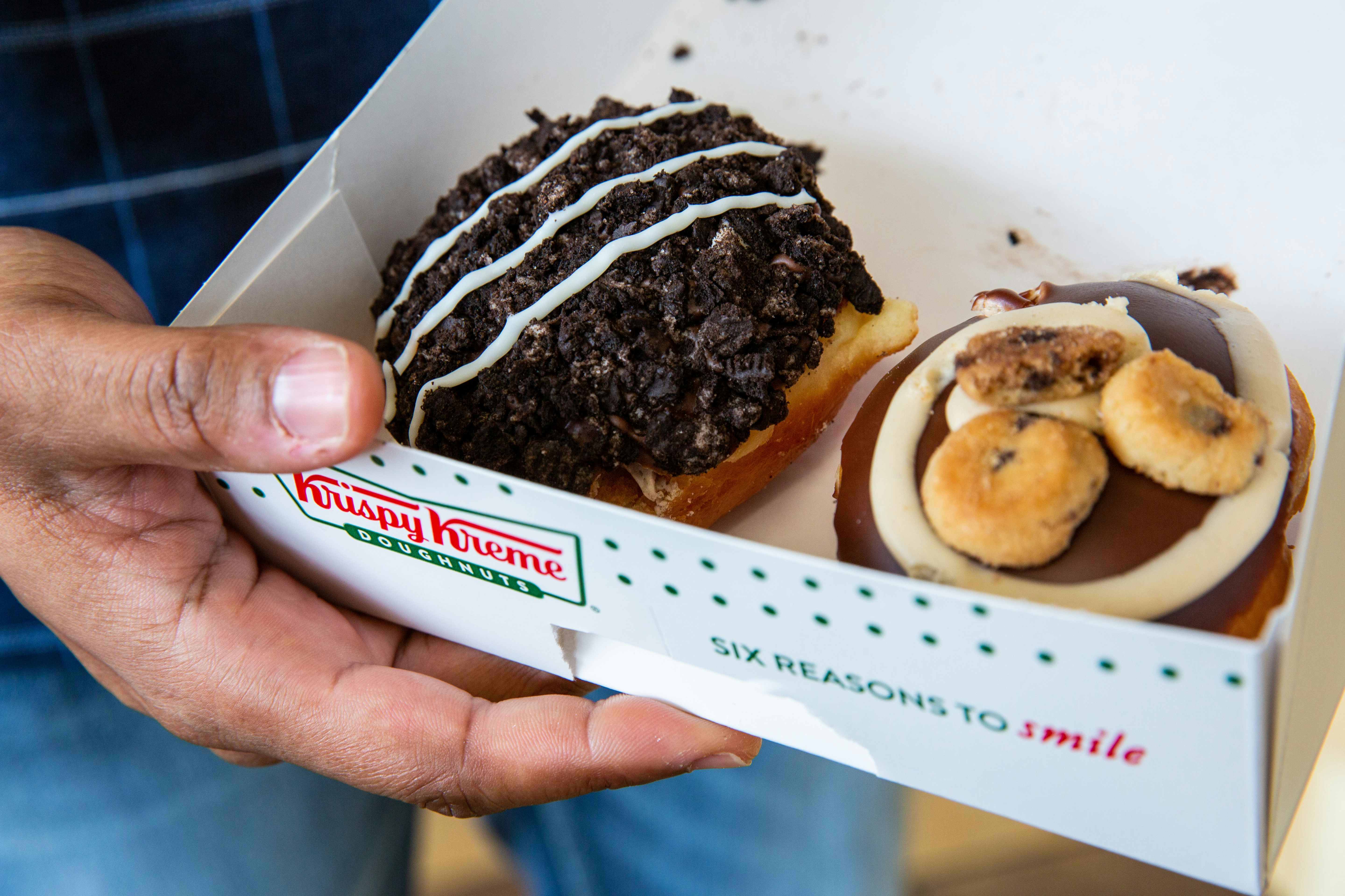 Hand holding a box of donuts from krispy kreme.