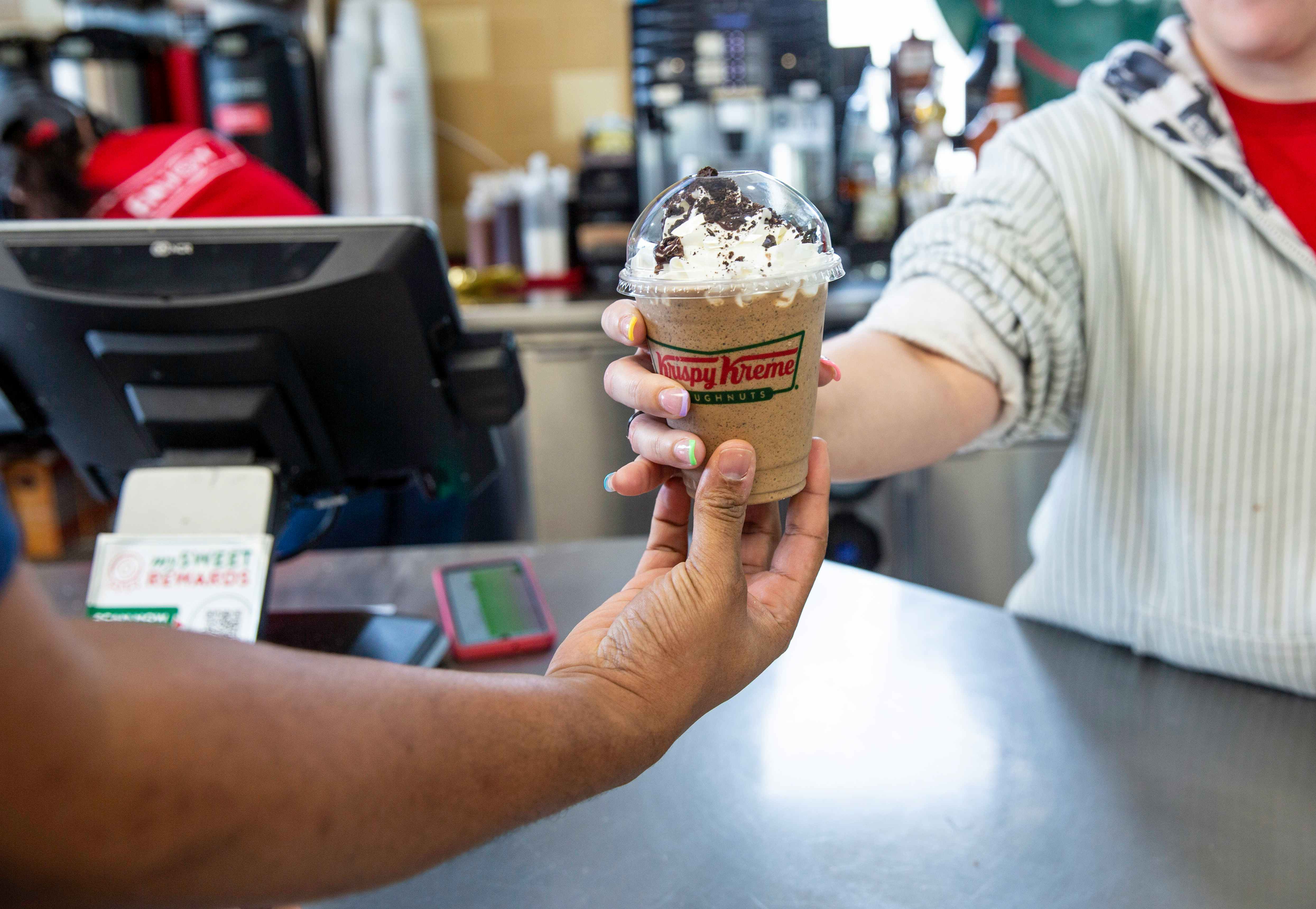 Employee handing over a limited edition oreo mocha latte to a customer