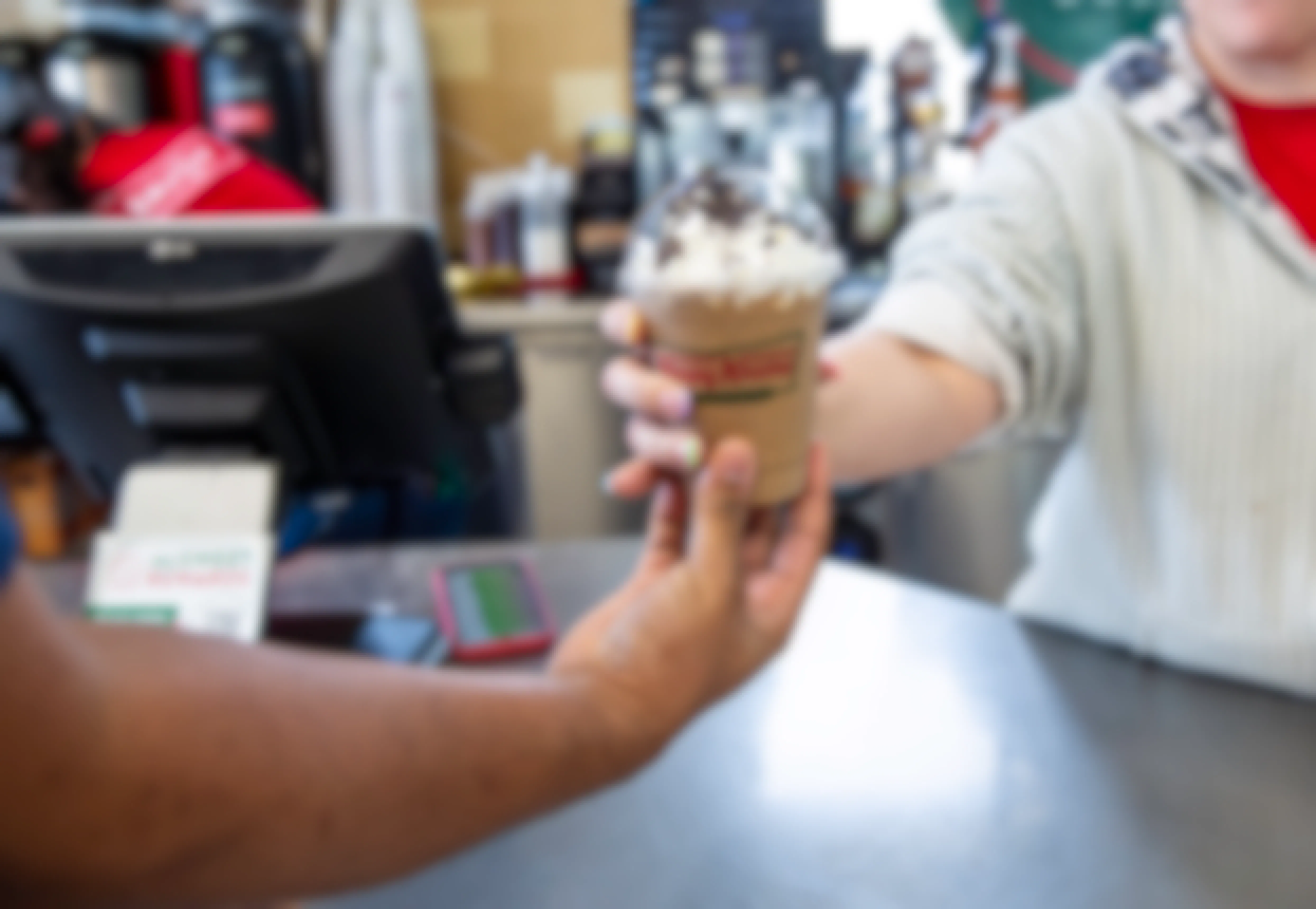 Employee handing over a limited edition oreo mocha latte to a customer