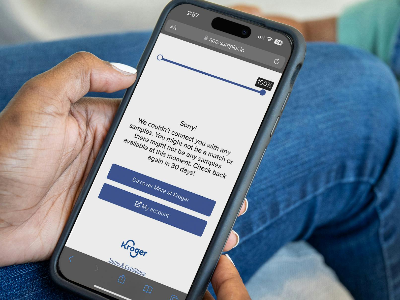 Someone holding a phone showing a message from the Kroger Sample Box survey saying they couldn't match the user to any samples, or that they ran out. It advises to try again in a month