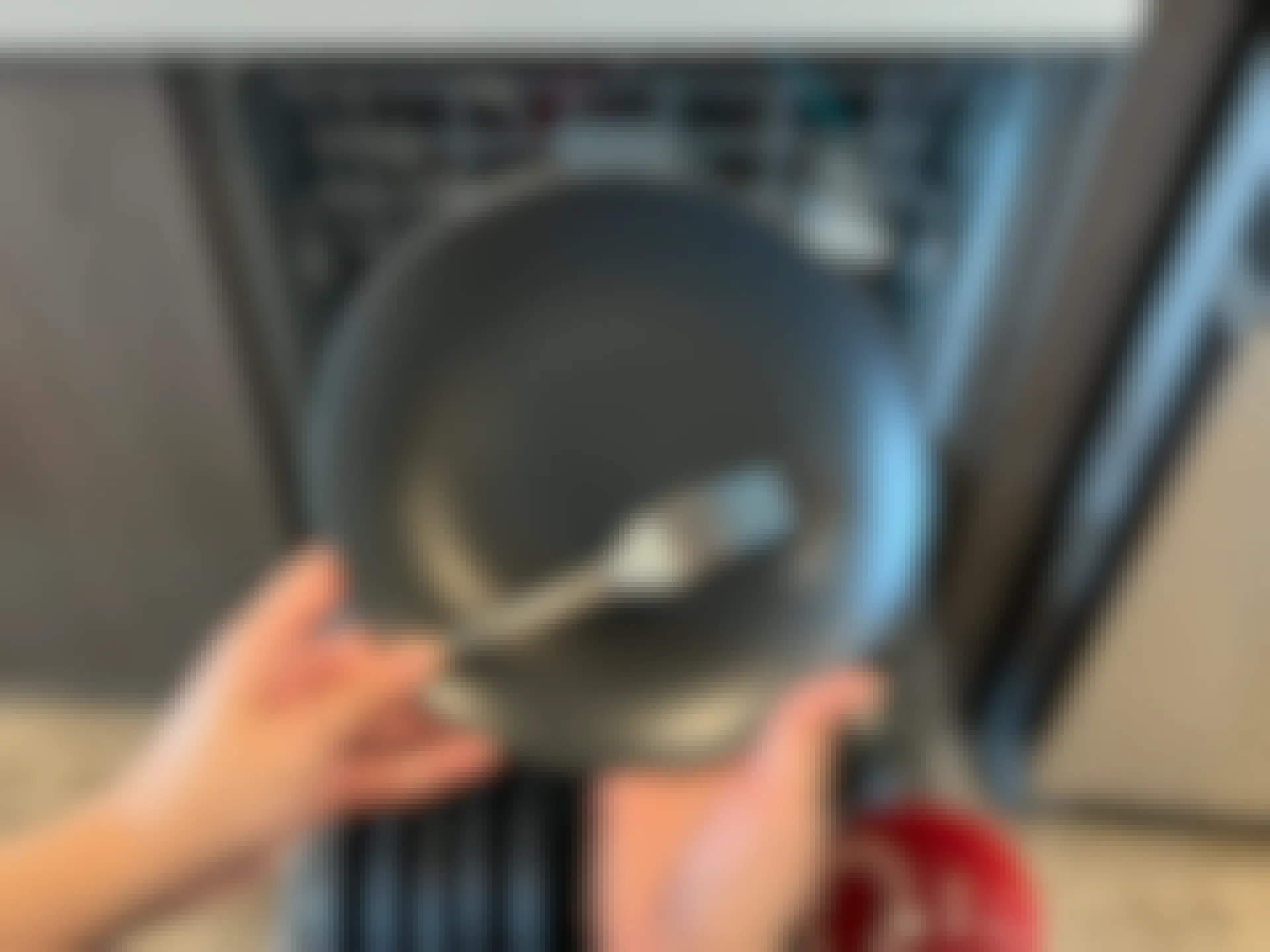 Hand holding a plate and fork in front of a dishwasher