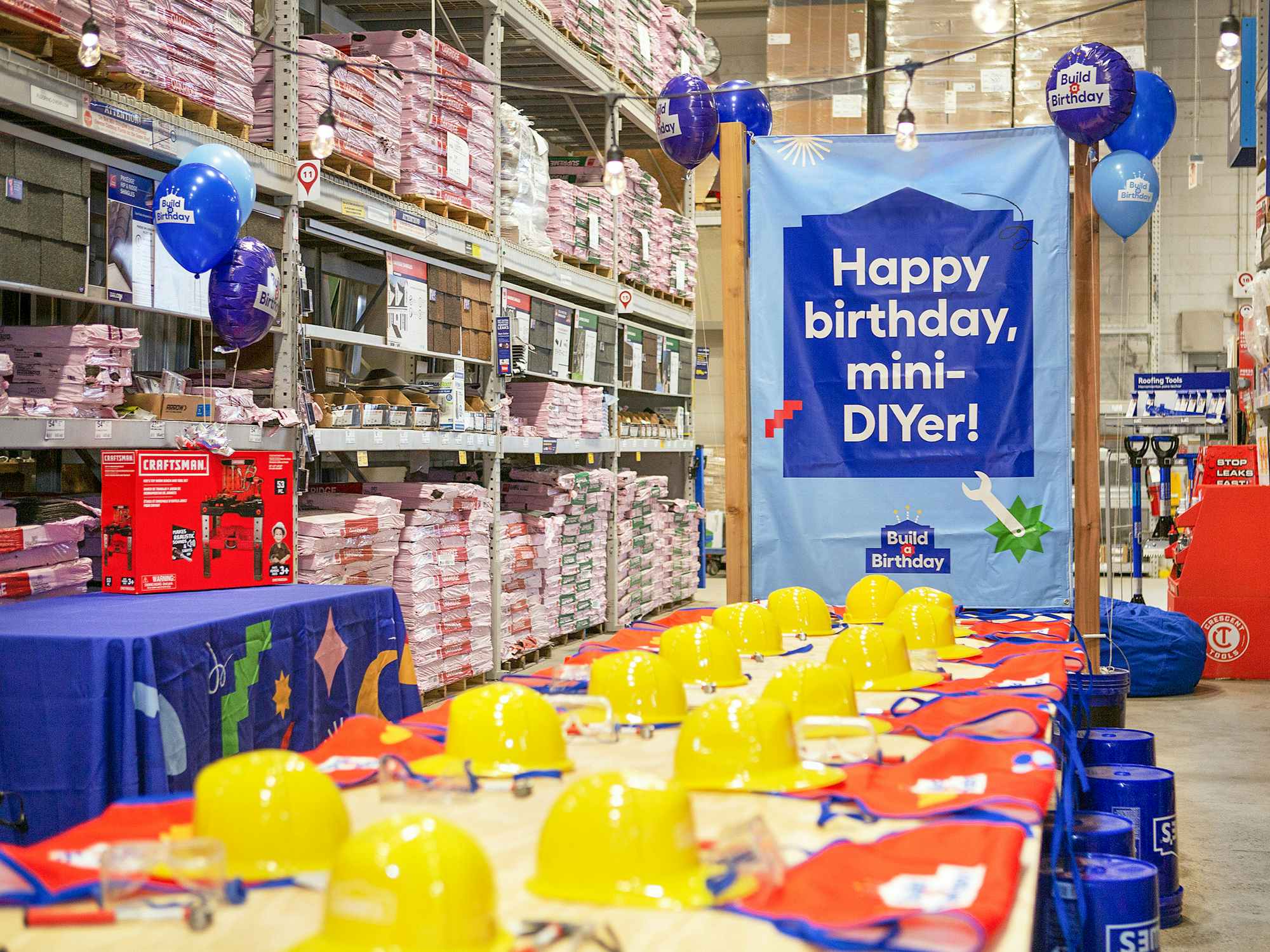 A Birthday party set up inside a Lowe's store with a sign that says "Happy Birthday mini DIY-er