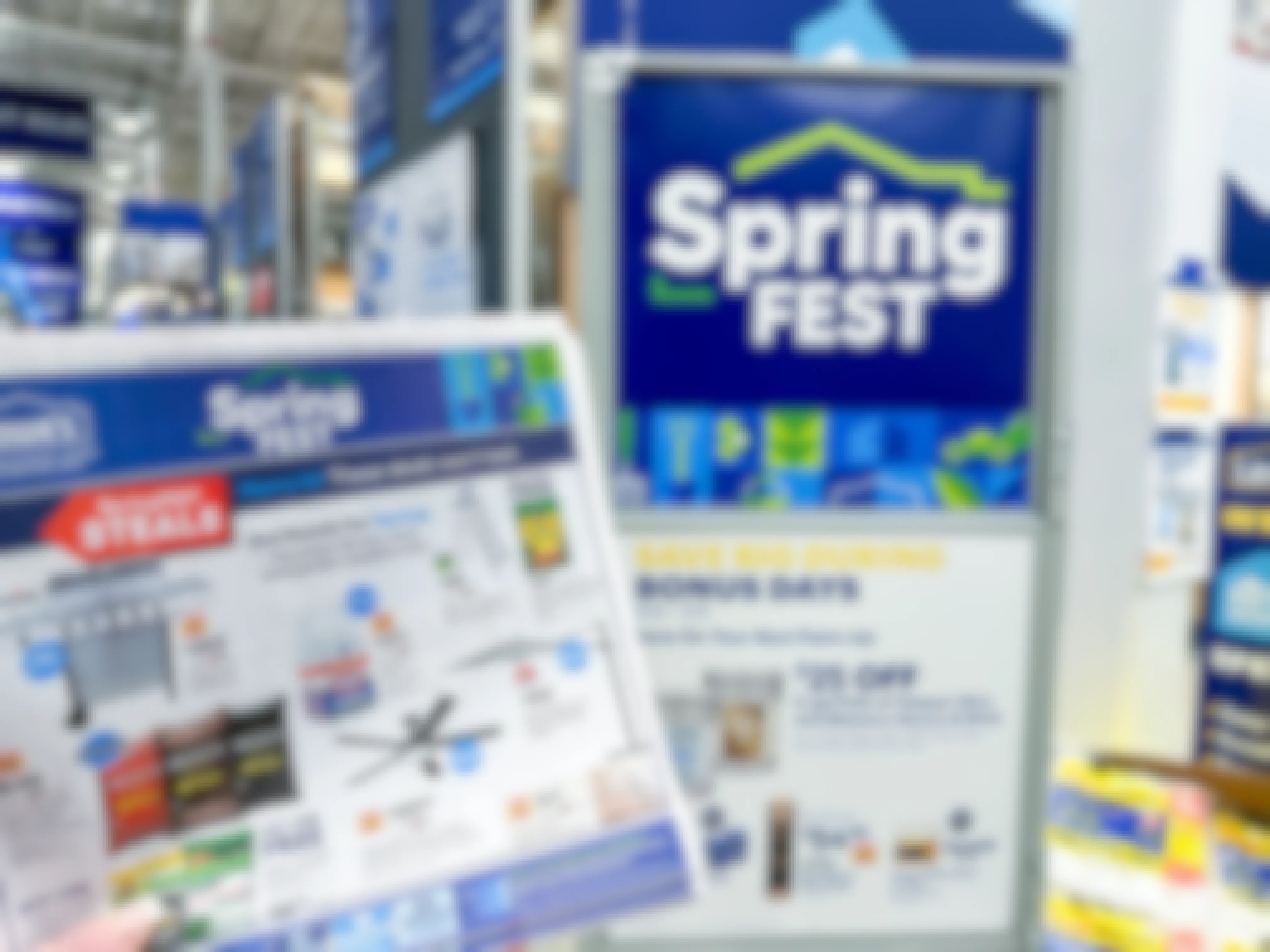 Someone holding up part of the Lowe's SpringFest 2023 ad next to a SpringFest sign at the Lowe's store