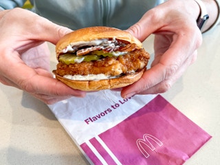 a person holding a mcdonalds mccrpisy sandwich