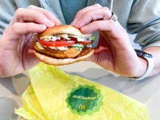 a person holding a mcdonalds mccrpisy sandwich