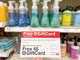 A variety of hand soaps sitting on store shelves with a Free Gift card sign attached to it.