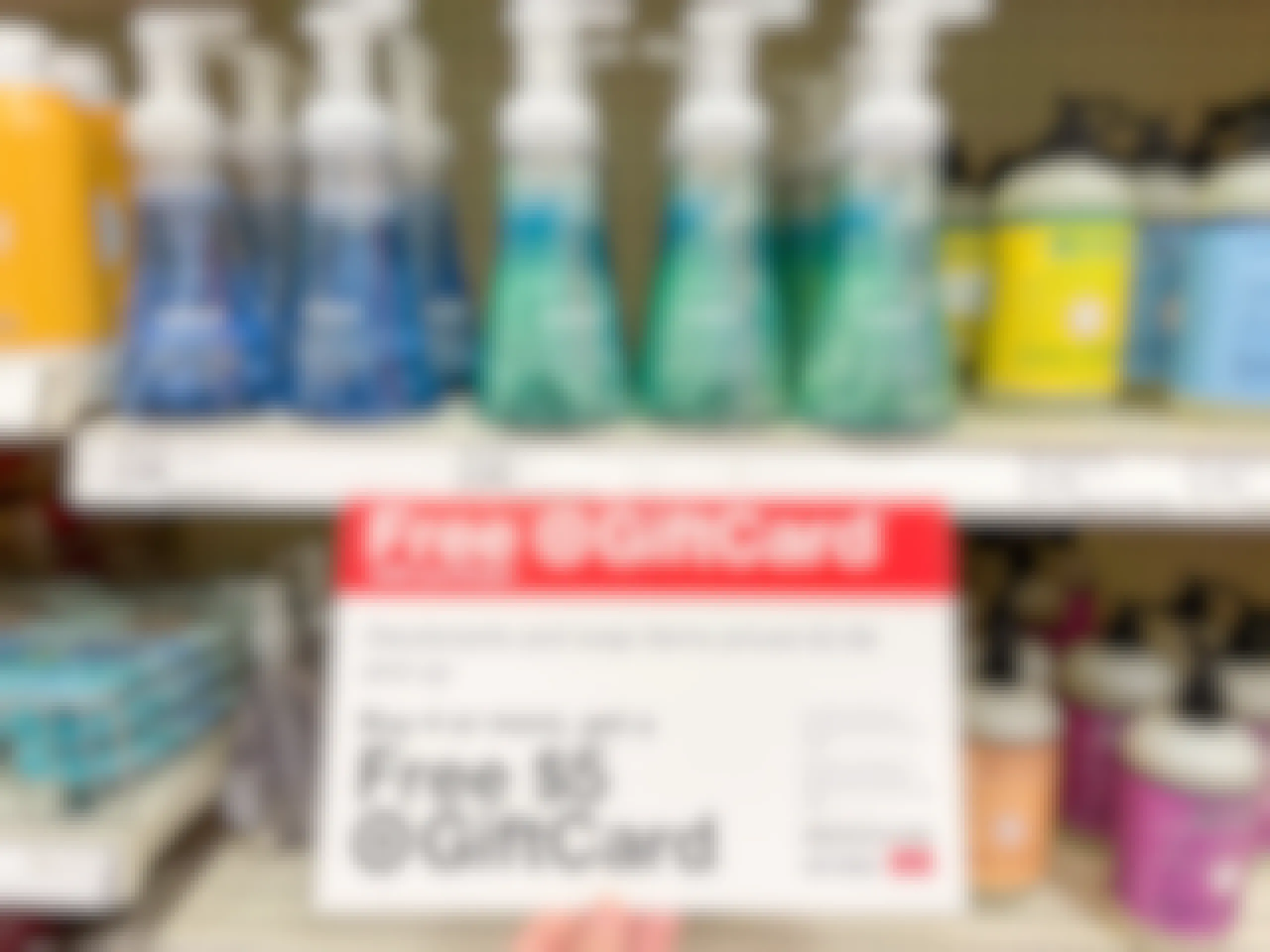 A variety of hand soaps sitting on store shelves with a Free Gift card sign attached to it.
