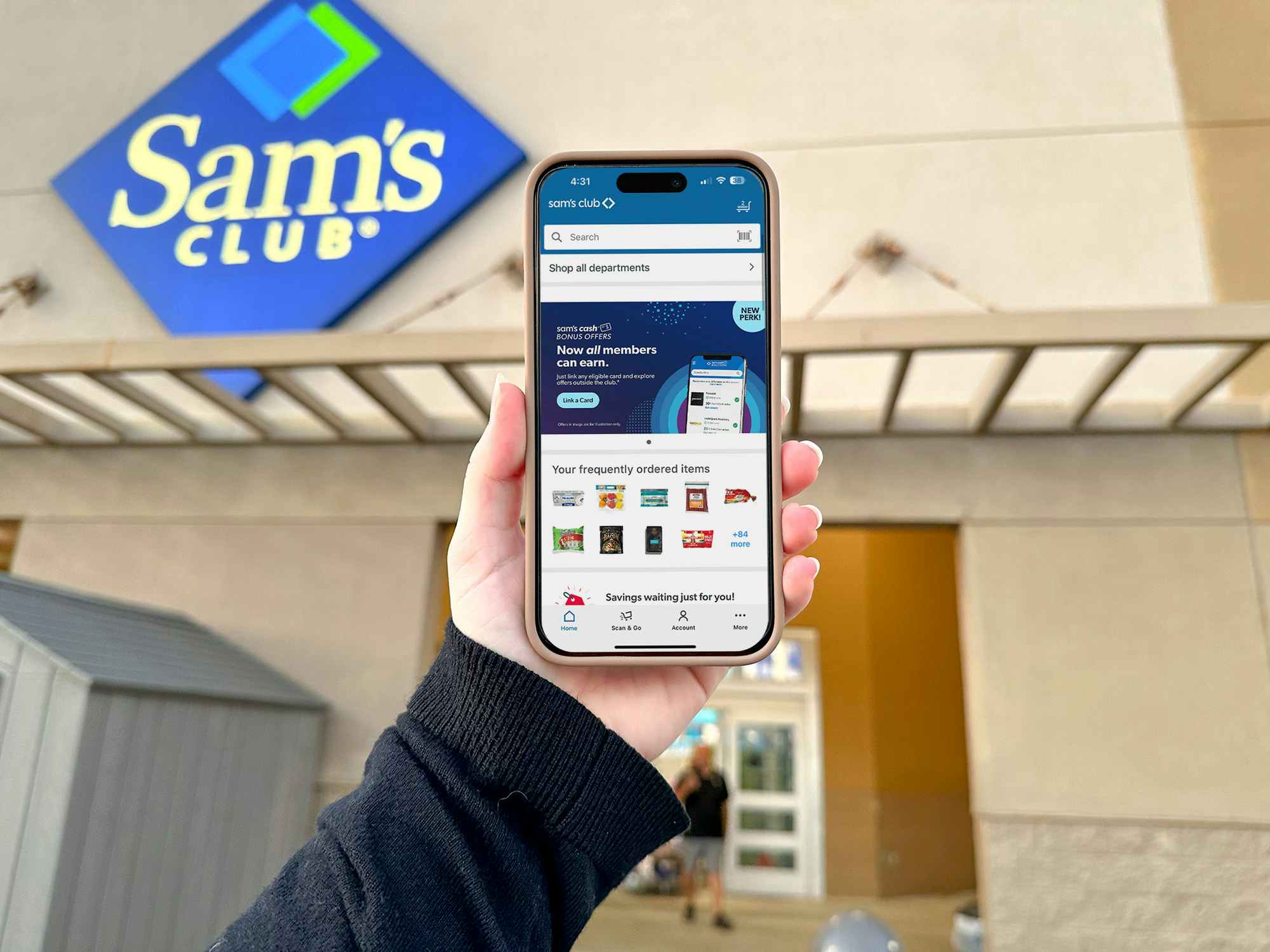 Someone holding up a phone displaying the Sam's Club app in front of Sam's Club