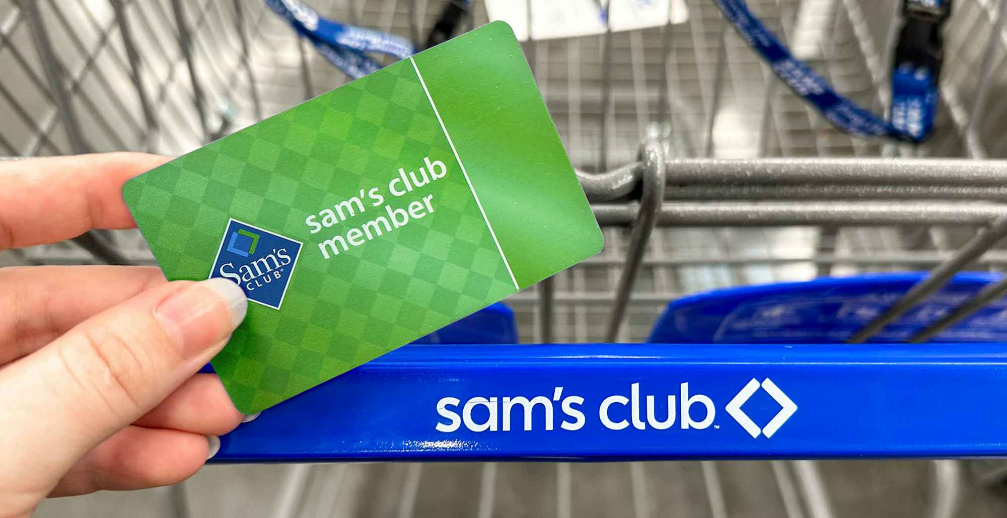Someone holding a Sam's Club membership card by a cart