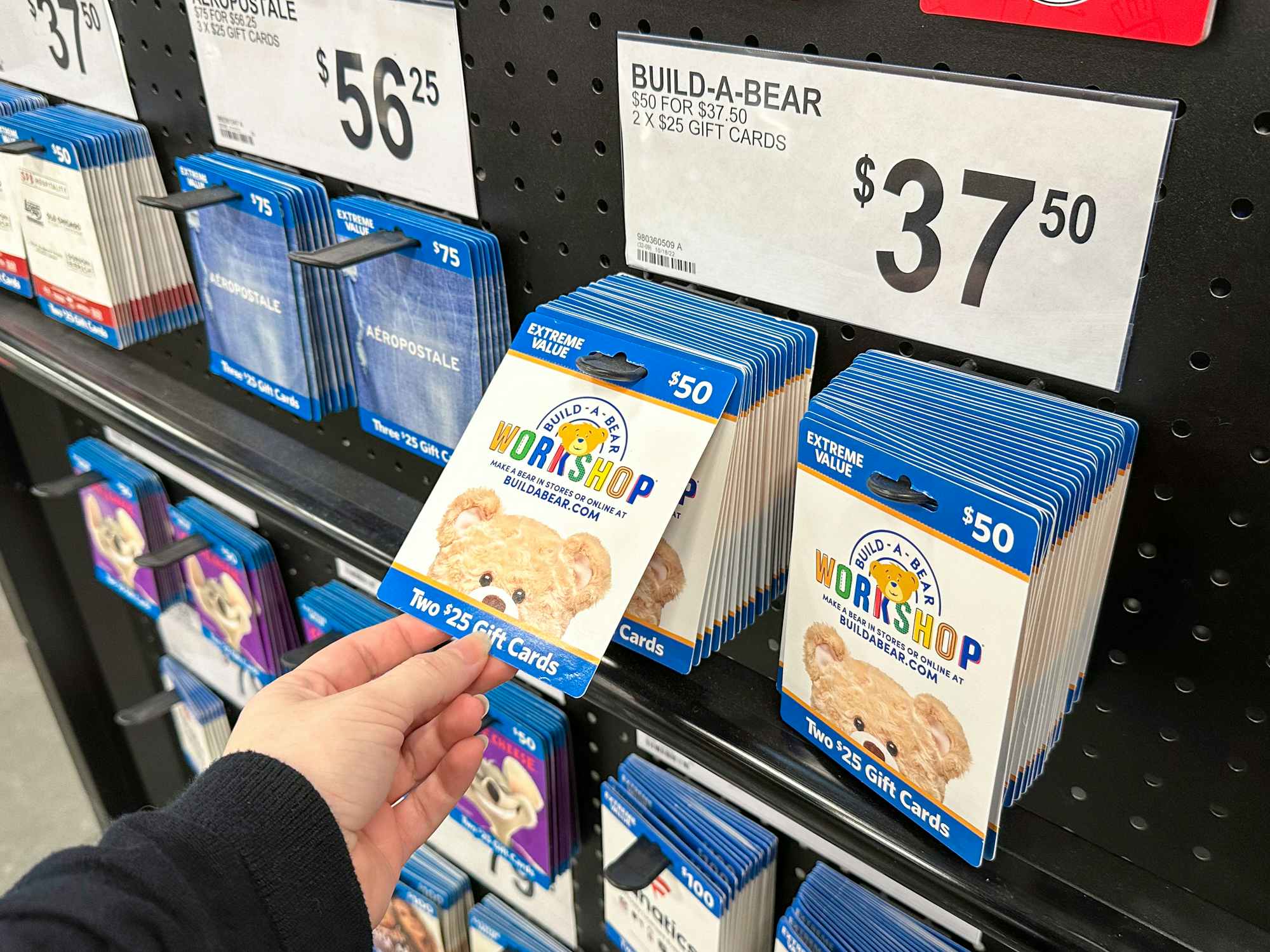 Someone taking a Build-a-Bear gift card from the Extreme Value gift card display in Sam's Club